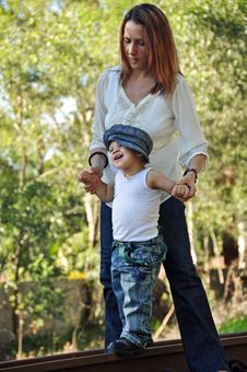 Young Mother Helping Toddler Baby Boy To Walk Stock Image