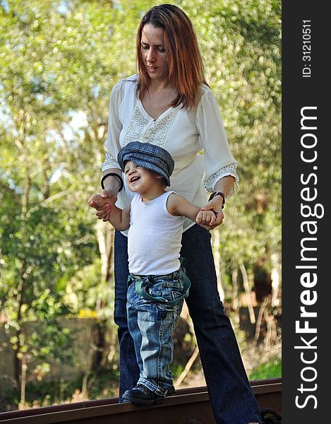 A soft portrait of an Australian young mum being very protective with her little baby boy and helping him to take his first steps. Photo was taken at an old abandoned railway track in Brisbane, Australia. A soft portrait of an Australian young mum being very protective with her little baby boy and helping him to take his first steps. Photo was taken at an old abandoned railway track in Brisbane, Australia.