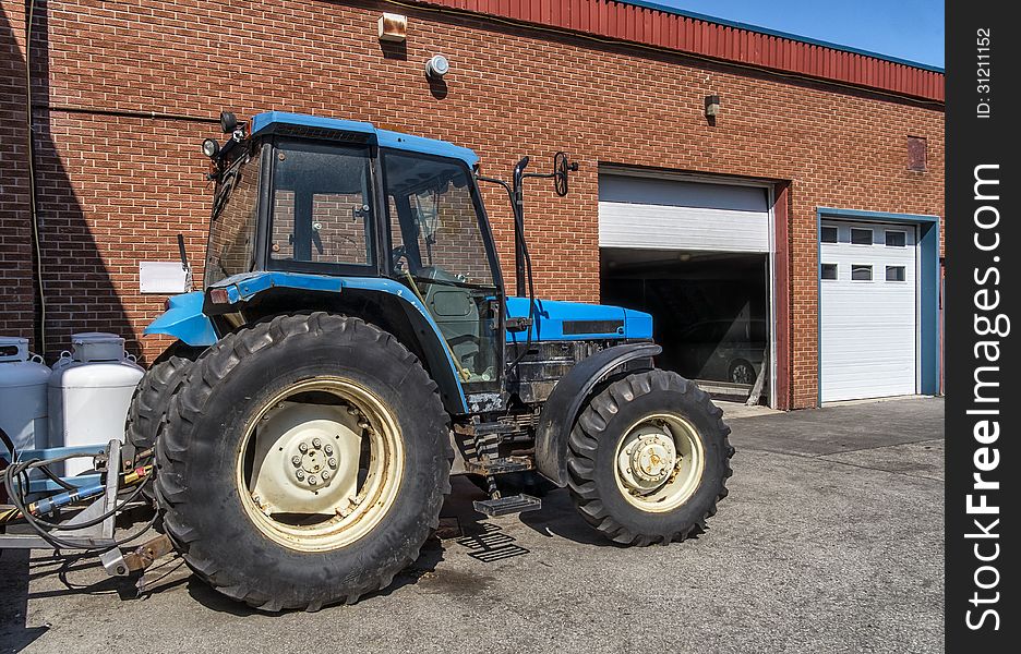 Blue tractor parked under a clean blue sky