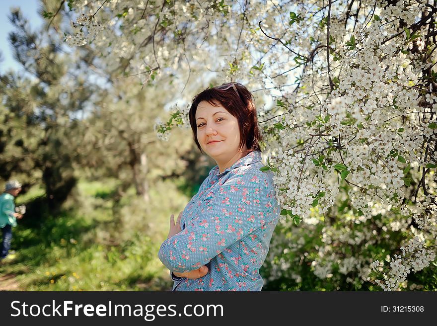 Girl in glasses on a background of a blossoming tree in spring in the garden
