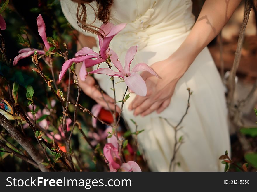 Pregnant woman's belly and soft hands with a beautiful pink flower. Pregnant woman's belly and soft hands with a beautiful pink flower