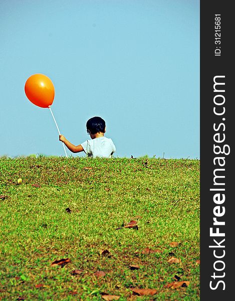 A kid running with flying balloon on green field. A kid running with flying balloon on green field.