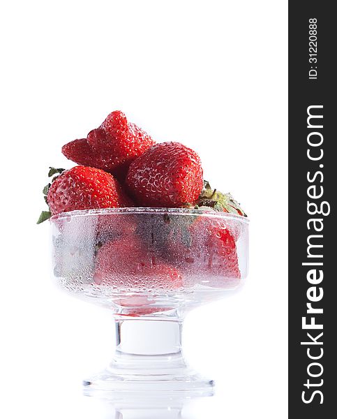 Dessert of strawberries in a bowl on a white background, reflected in the table