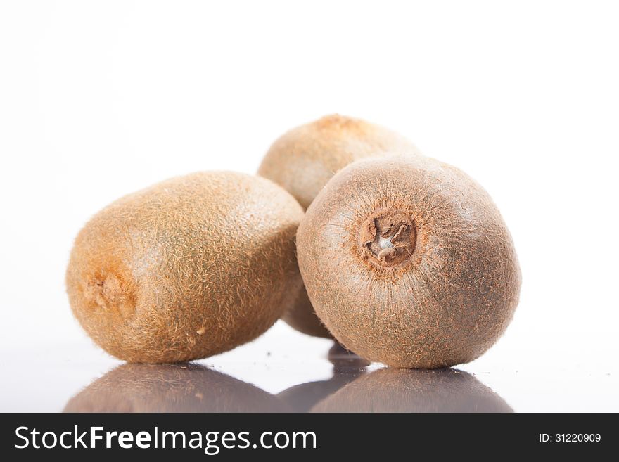 Kiwi fruit on a white background, reflected in the table. whole fruit. Kiwi fruit on a white background, reflected in the table. whole fruit.