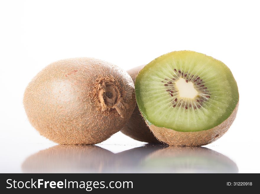 Kiwi fruit on a white background, reflected in the table. whole and sliced ​​fruit.