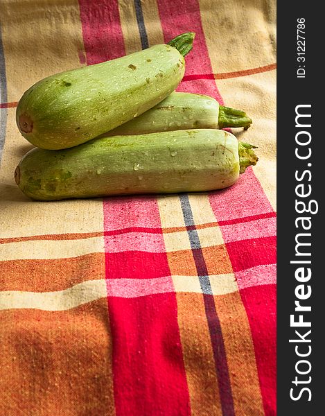 Washed green vegetables. Wet zucchini on a colored tablecloths.