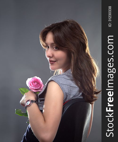 Portrait of a beautiful young girl with a pink rose