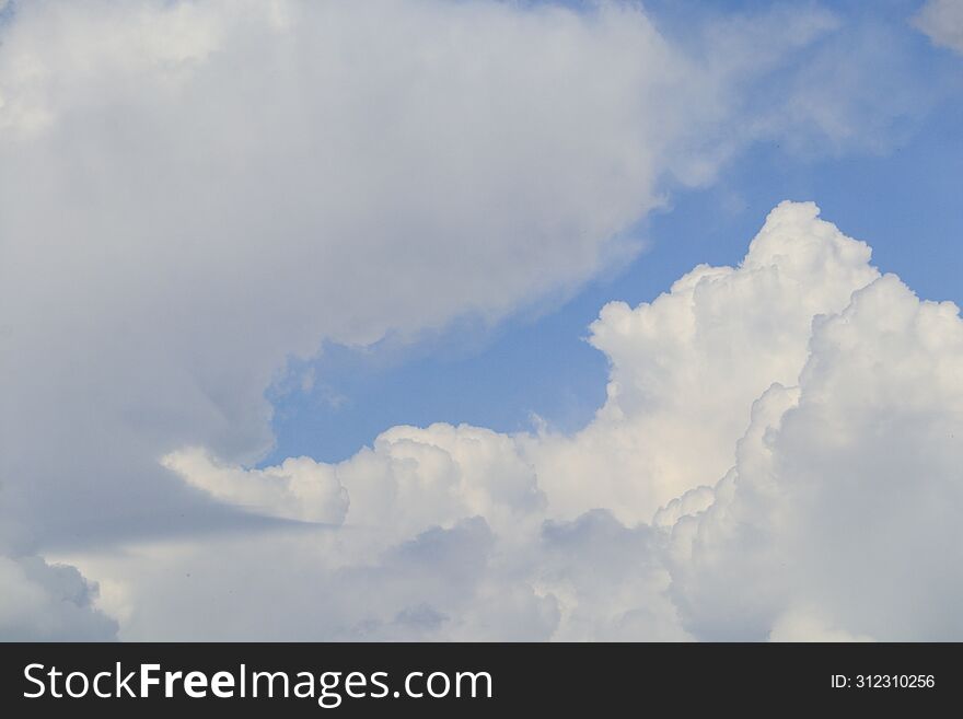 White Large Voluminous And Gray Cumulus Clouds In The Blue Sky On A Spring Day