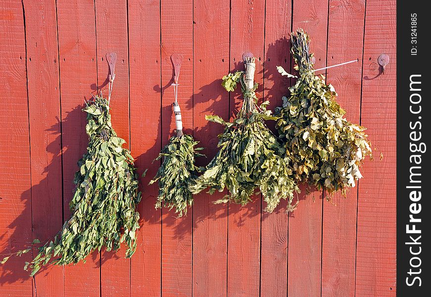 The birch broom hangs in a bath on a wooden wall. The birch broom hangs in a bath on a wooden wall