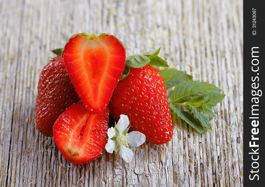 Fresh strawberries and two halves on a wood background. Fresh strawberries and two halves on a wood background