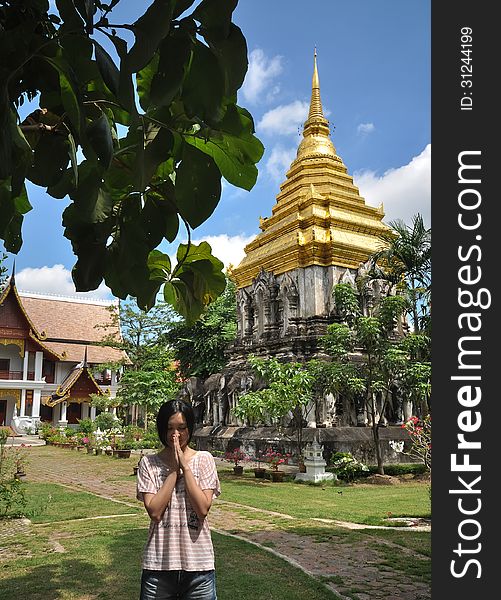 Single beautiful young girl praying in ancient Wat Chiang Man temple, one of the landmark in Chiang Mai, Thailand. Single beautiful young girl praying in ancient Wat Chiang Man temple, one of the landmark in Chiang Mai, Thailand