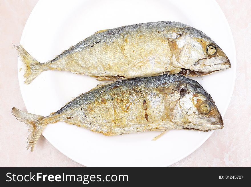 Two fried mackerel fishes on white plate