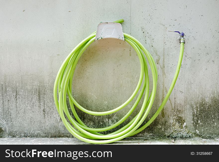 Green rubber tube on be dirty wall