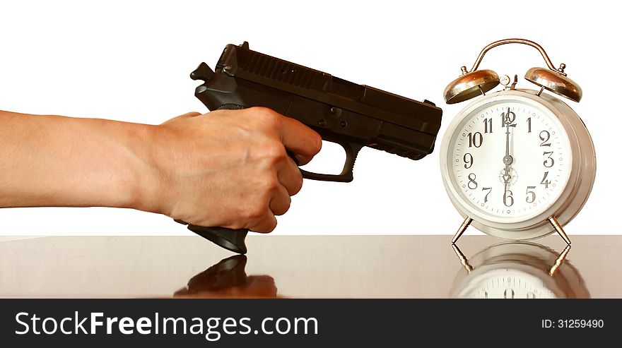 A hand with gun ready to fire at an alarm clock. A hand with gun ready to fire at an alarm clock