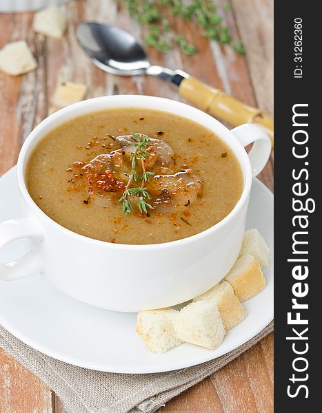 Mushroom cream soup with croutons and thyme in a bowl vertical