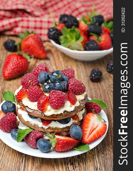 Pancake cake with whipped cream and fresh berries, closeup, bowl of berries in the background. Pancake cake with whipped cream and fresh berries, closeup, bowl of berries in the background