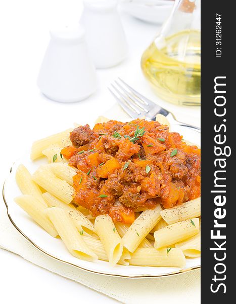 Penne pasta with sauce of beef, tomato and pumpkin on a plate isolated on white background, vertical