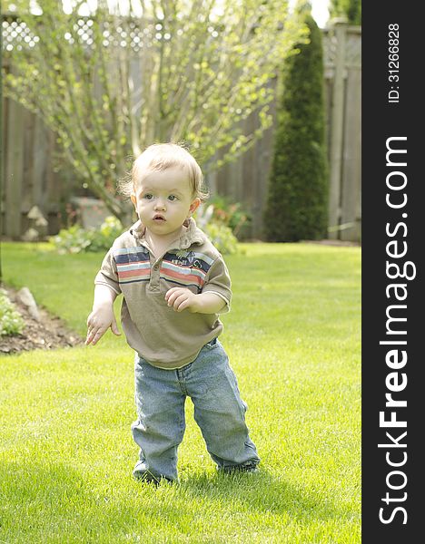 A young toddler is learning to walk on grass. A young toddler is learning to walk on grass