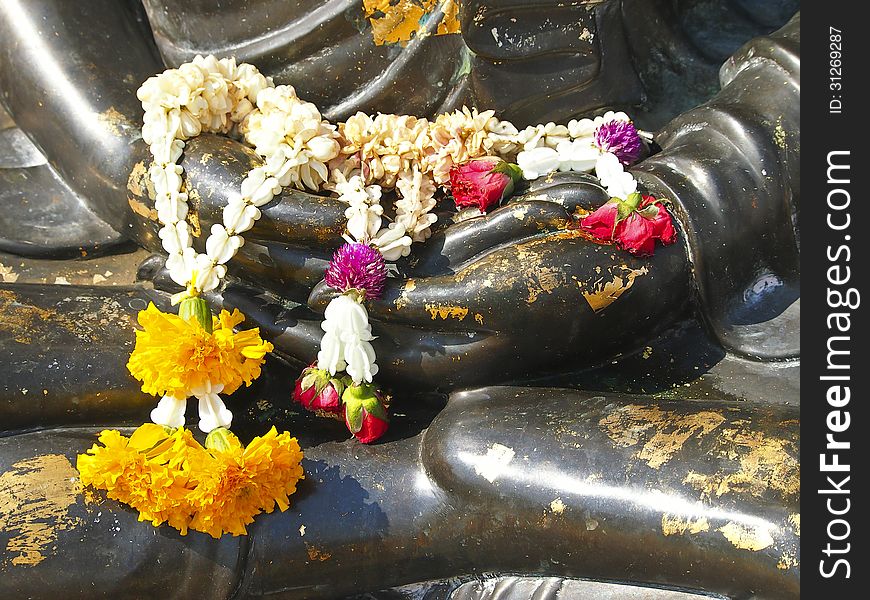 Garland on lap of black Buddha statue for worship