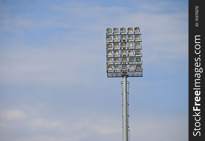 High pole of football stadium floodlight in cloudy sky. High pole of football stadium floodlight in cloudy sky