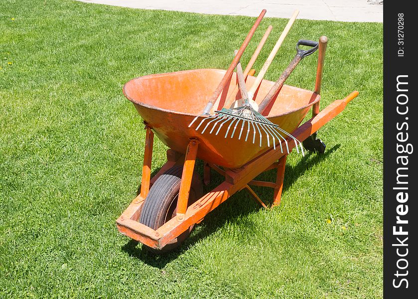 Orange wheelbarrow with garden tools