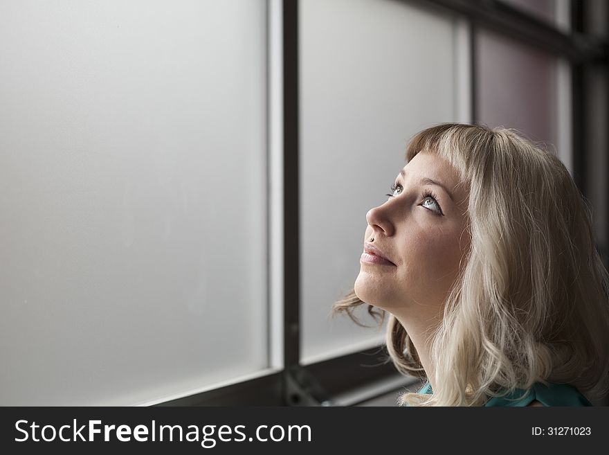 Portrait of a beautiful young woman with brown and blond hair looking up in the air.