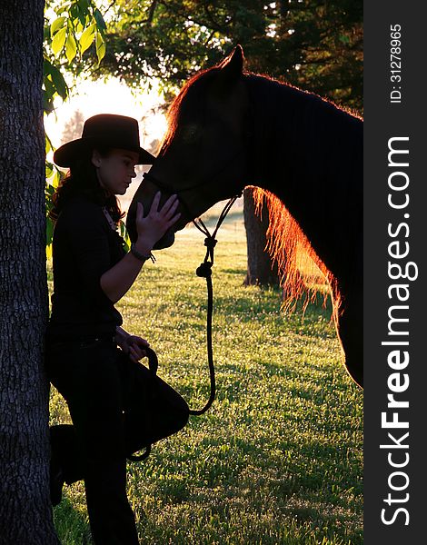 A cowgirl bonds with her horse at sunrise on the farm. A cowgirl bonds with her horse at sunrise on the farm