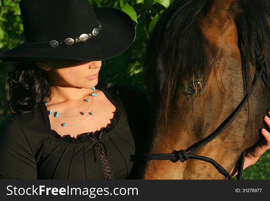 A cowgirl bonds with her horse at sunrise on the farm. A cowgirl bonds with her horse at sunrise on the farm