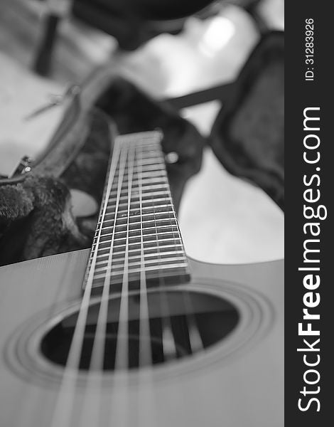 An acoustic guitar seen by the side, with strings out of focus