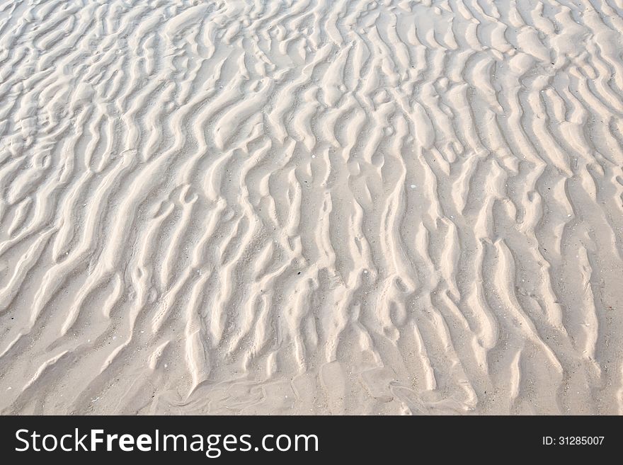 Wet sand by sea water texture.