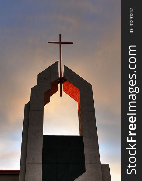 This photo of a church steeple with a cross on the very top was taken just as the sun was going down. The light from the setting sun was reflected off the inside of where the cross was attached and the timing of the photo still provided some blue sky and colorful clouds. This photo of a church steeple with a cross on the very top was taken just as the sun was going down. The light from the setting sun was reflected off the inside of where the cross was attached and the timing of the photo still provided some blue sky and colorful clouds.