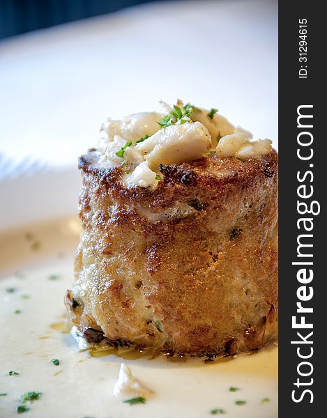 This is a off center, close up picture of a crab cake with bits of crab on top.