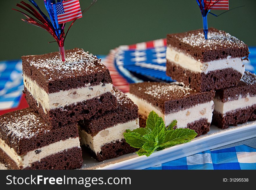 These are patriotic brownies, with ice cream in the middle, covered in powdered sugar with a mint leaf in front. Chocolate brownie with vanilla ice cream