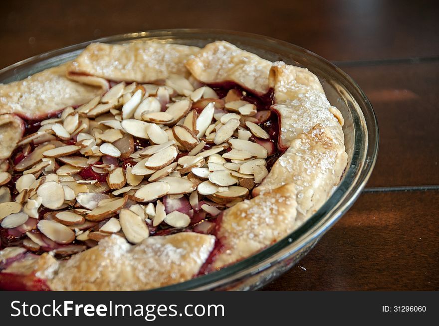 This is a homemade berry pie with sugar on the crust and topped with almonds.