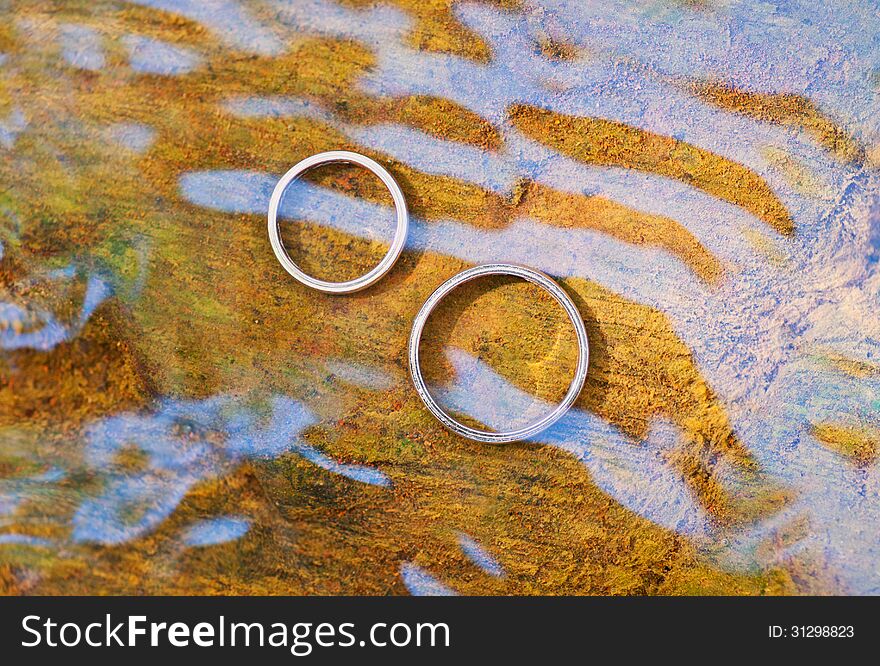 Wedding rings in water with reflections