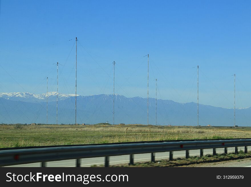 The Antenna Field Of The Radio Center Against The Backdrop Of High Snow-capped Mountains, Visible From The Highway On A Clear Day