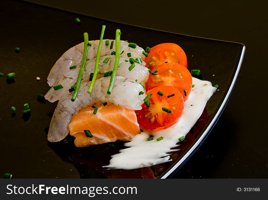 Fresh salmon slice on white platter with salad and prawns served with yogurt cream