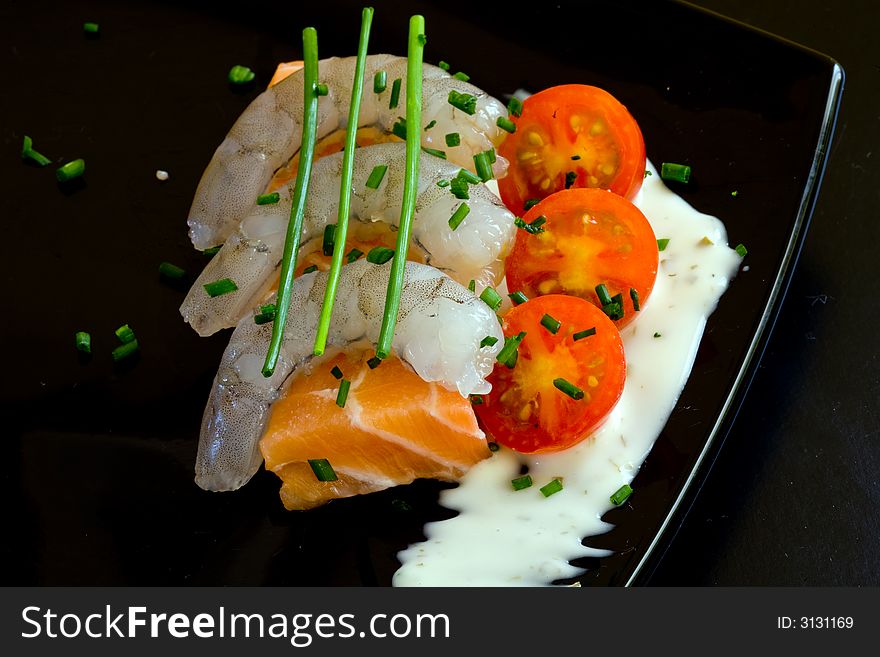 Fresh salmon slice on white platter with salad and prawns served with yogurt cream