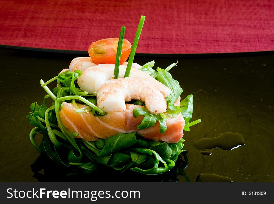 Fresh salmon tartar on black platter with rocket salad