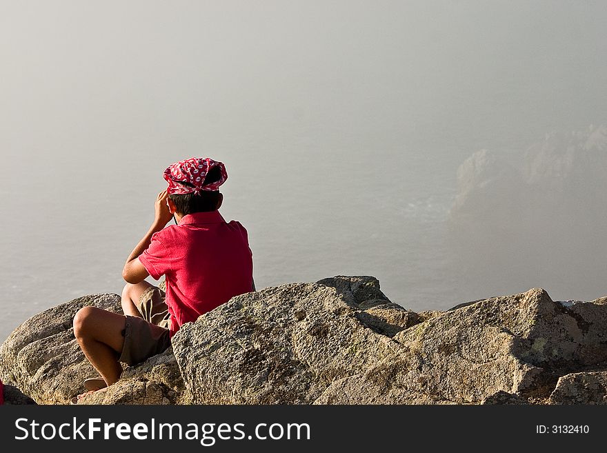 A boy is taking a look around on a peak along the foggy coast of Brittany, France. A boy is taking a look around on a peak along the foggy coast of Brittany, France