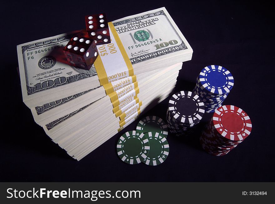 Stack of Hundred Dollar Bills, Poker Chips & Red Dice on a black background.