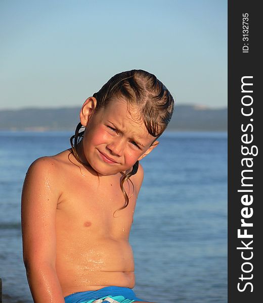 Little child sitting on the stone on the beach in summer. Little child sitting on the stone on the beach in summer