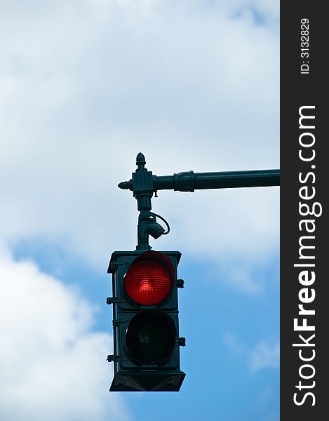 A red stop light overhead against a cloudy blue sky. A red stop light overhead against a cloudy blue sky