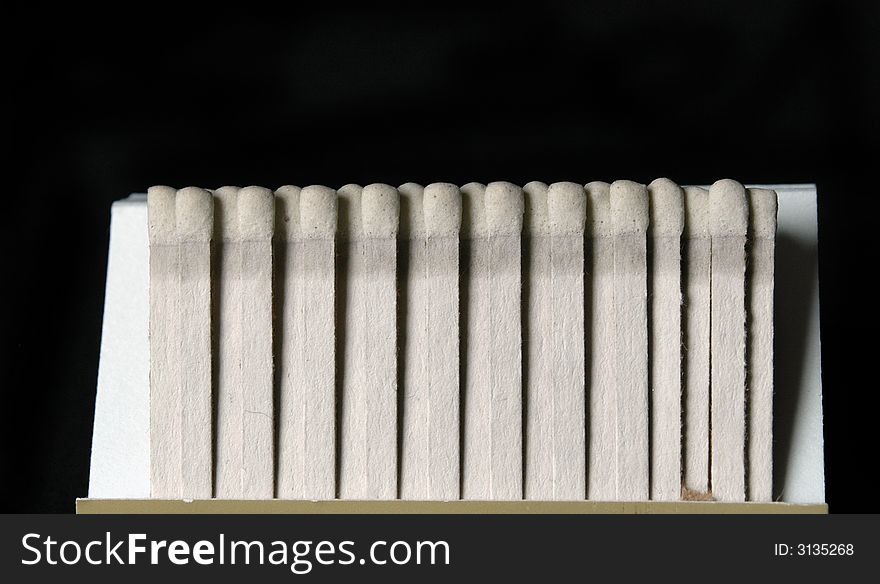 A tan book of white matches isolated on a black background. A tan book of white matches isolated on a black background.