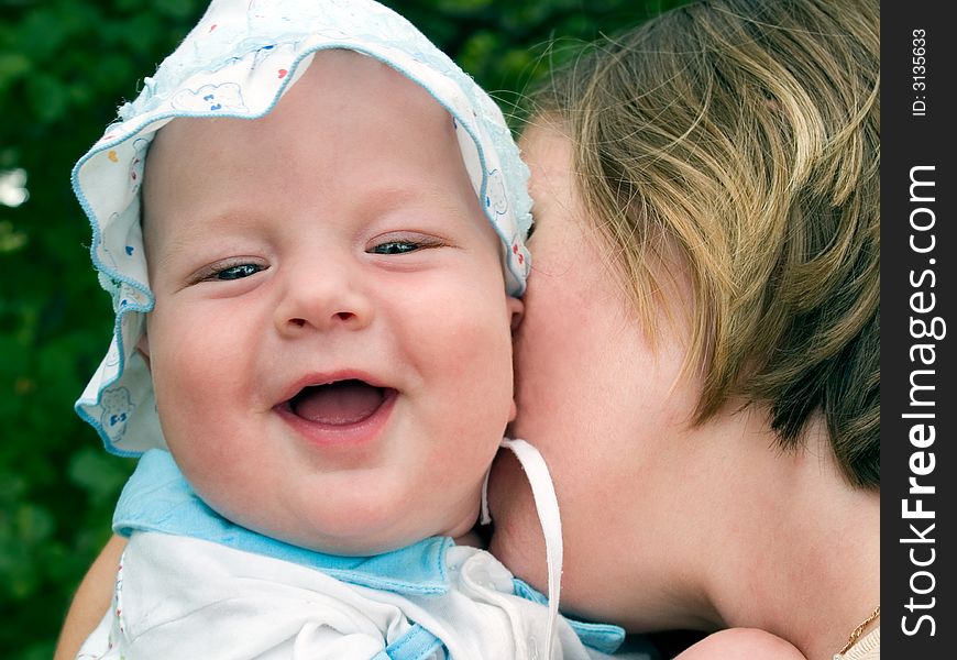 Family outdoor scene. Mother kissing laughing happy baby. Family outdoor scene. Mother kissing laughing happy baby.
