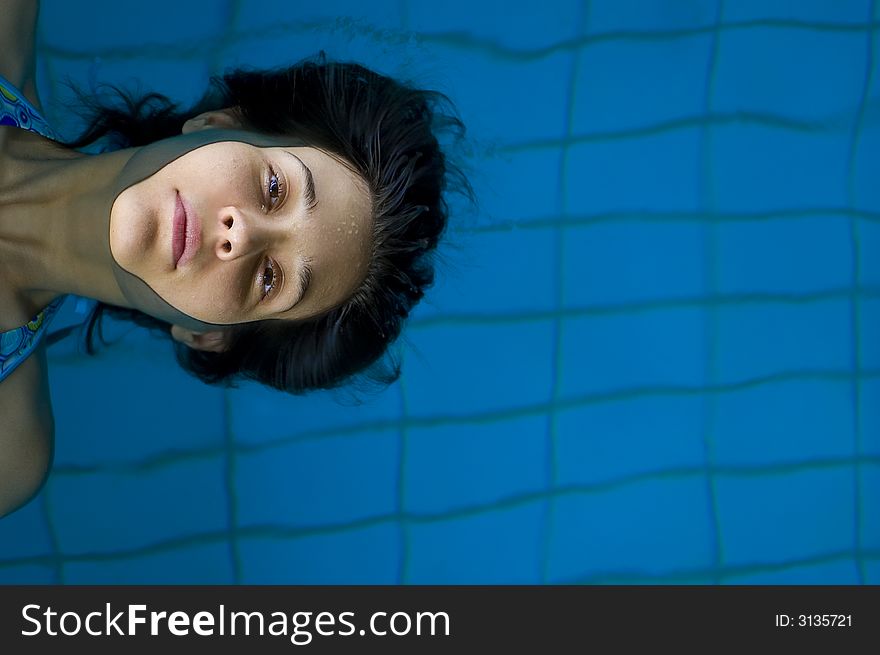 Attractive young girl relaxing in pool and swim
