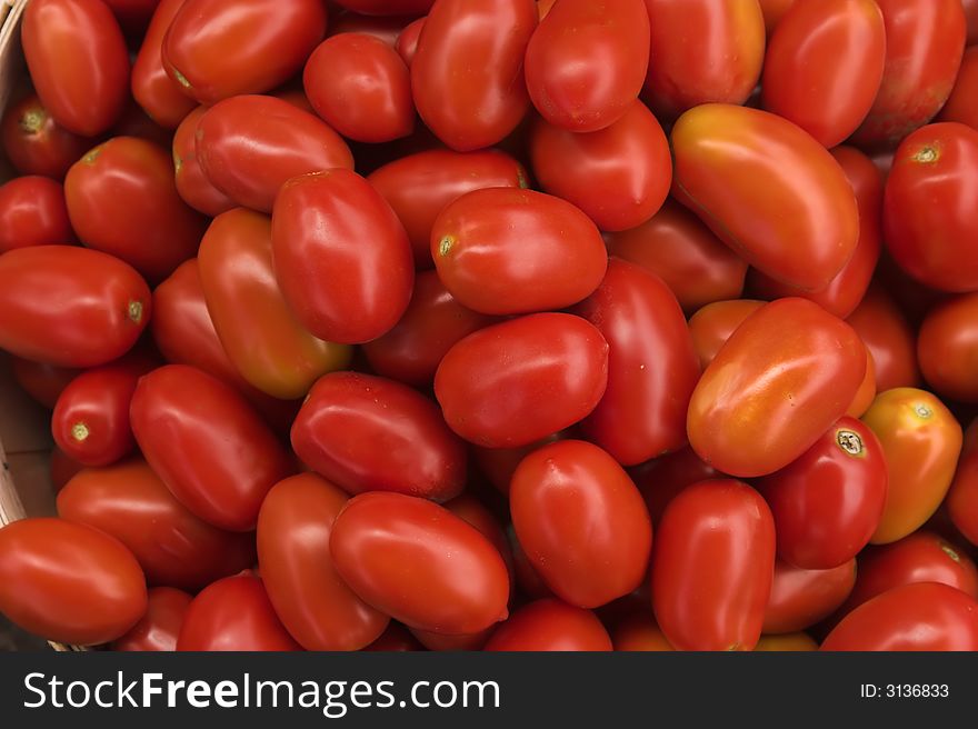 Pile of small red tomatoes for sale at a farmer's market.
