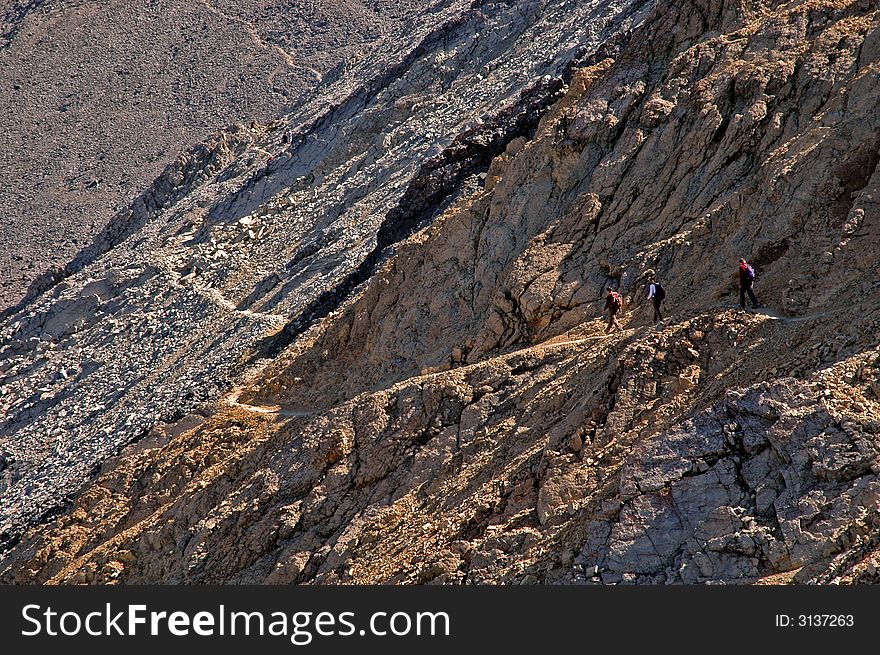 Several people climbing along rocky ridge on a trail. Several people climbing along rocky ridge on a trail