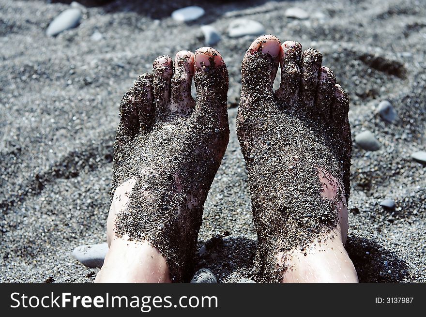 Male feet in pebbles on the beach