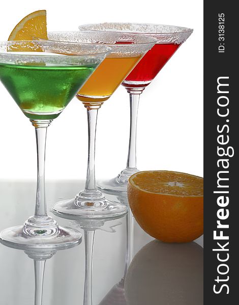 A photo of martini glass with green, orange, red cocktails and a piece of citrus. A photo of martini glass with green, orange, red cocktails and a piece of citrus